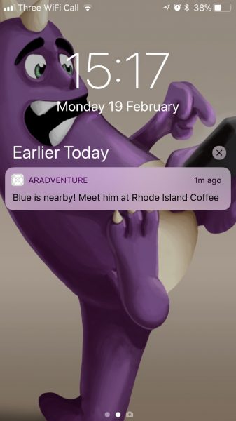 A screenshot of a phone lock screen with a notification indicating that the next character is at a nearby coffee shop